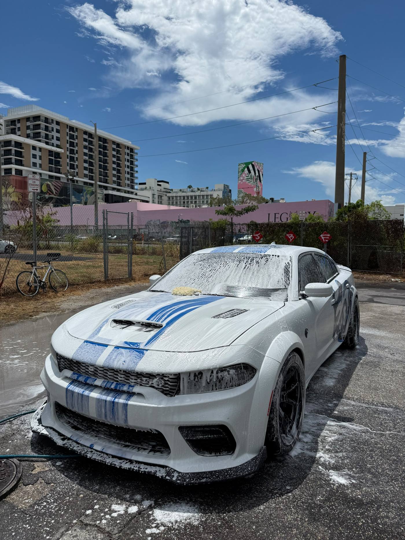 White Dodge Charger widebody covered in foam during a mobile detail wash